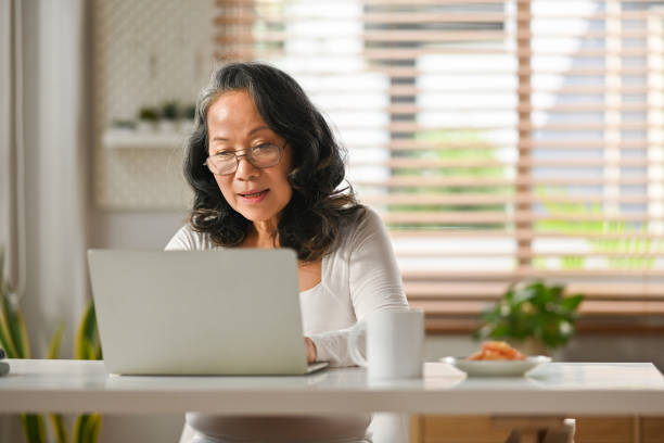 istock Beautiful senior woman entrepreneur working remote from home, reading email on laptop computer. 1479951148