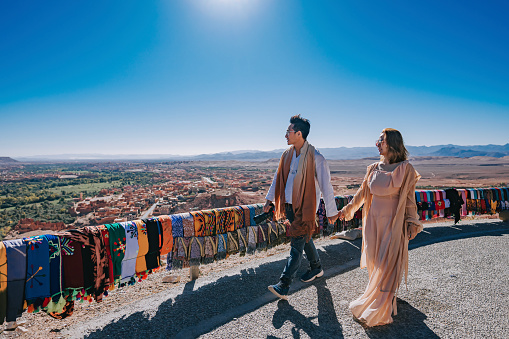 Asian Chinese couple tourist looking at a view from high angle hill side at Tinghir, Morocco