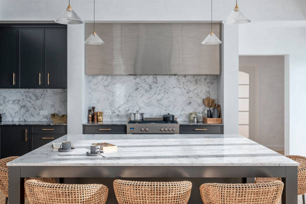Large modern gray kitchen with rectangular white and gray marble breakfast kitchen island with rattan stools stock photo