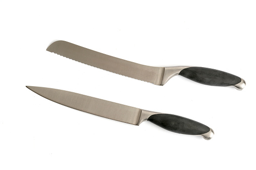 Five stainless steel knives atop cutting board against black background