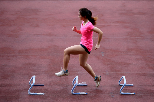 An Asian young woman is focusing on routine athletic training in stadium