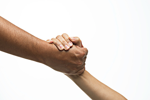 Two unrecognizable caucasian peoples hands are holding each others wrist in front of pure white background. Arms are forming a diagonal line from the right upper corner to the left bottom corner.