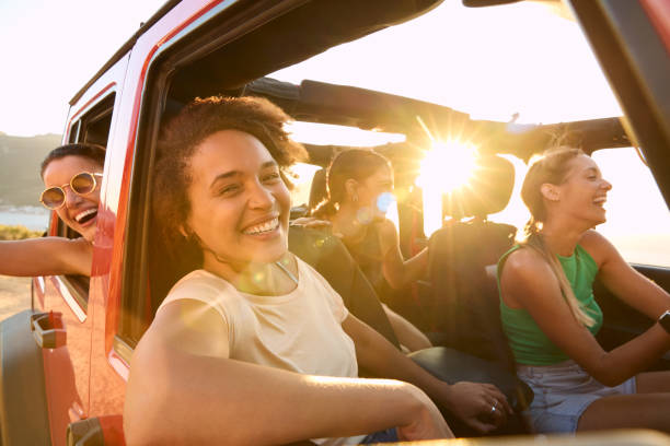 Portrait Of Laughing Female Friends Having Fun In Open Top Car On Road Trip stock photo