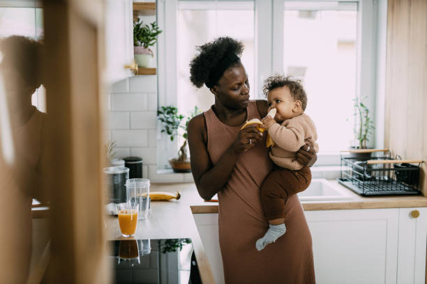 istock Mom making freshly squeezed juice and feeding her baby boy in the kitchen 1479965444