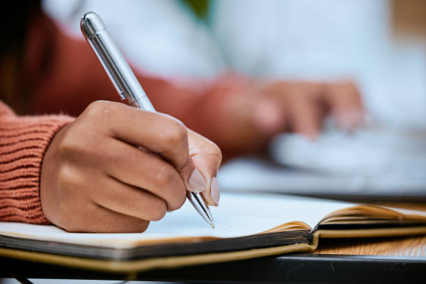 istock Student, writing and zoom of hand with notebook for studying, learning and notes in academic class. University, college and closeup of hands with pen to write schedule information, planning and ideas 1479969398