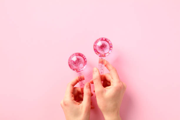Female hands holding two ice globes for facials on pink background