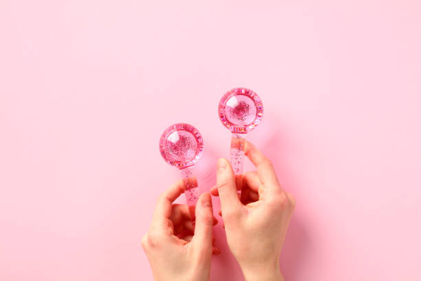 Female hands holding two ice globes for facials on pink background stock photo