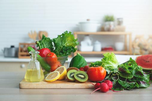 Fresh fruits and vegetables on wooden table in bright white kitchen, healthy lifestyle concept