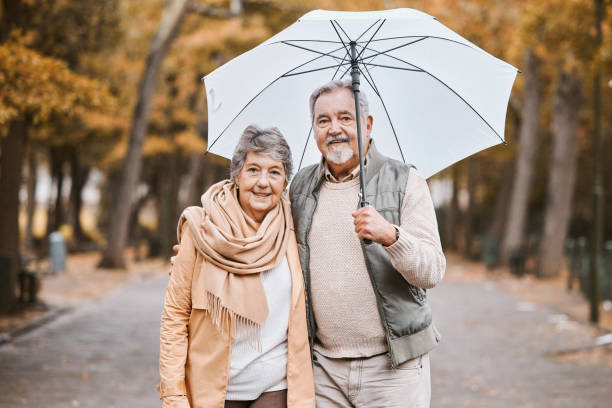 冬、公園での抱擁と老夫婦、退職日、傘を持ってカナダを歩く。幸福と愛のために散歩する老人と女性の自然の愛情、笑顔、肖像画 - africa senior adult friendship men ストックフォトと画像