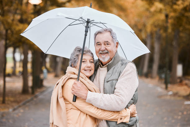 冬、公園での抱擁と老夫婦、退職日、傘を持ってカナダを歩く。幸福と愛のために散歩する老人と女性の自然の愛情、笑顔、肖像画 - africa senior adult friendship men ストックフォトと画像
