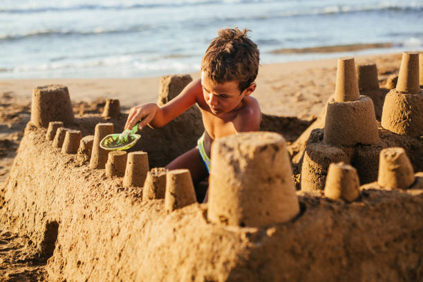 Boy making a sand castle on the beach Little boy playing in the sand ,making a sand castle sand castle stock pictures, royalty-free photos & images