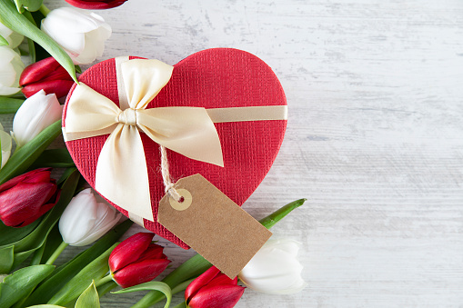 Mother’s Day and Valentine’s Day concept with red and white tulips and heart shaped gift box