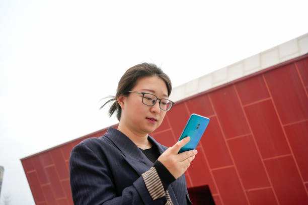 le donne d'affari usano i telefoni cellulari sulla strada - credit card analyzing internet mobility foto e immagini stock