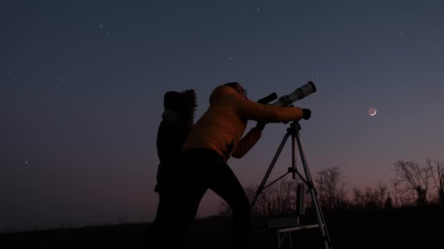 Woman and man with astronomy telescope looking at the night sky, stars, planets, Moon and shooting stars.