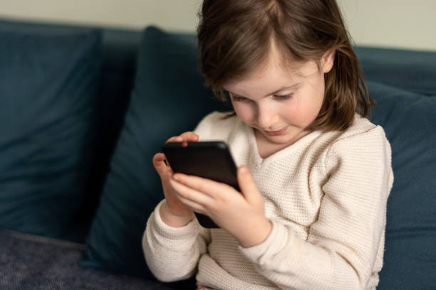 istock Little girl using mobile phone at home 1479985310