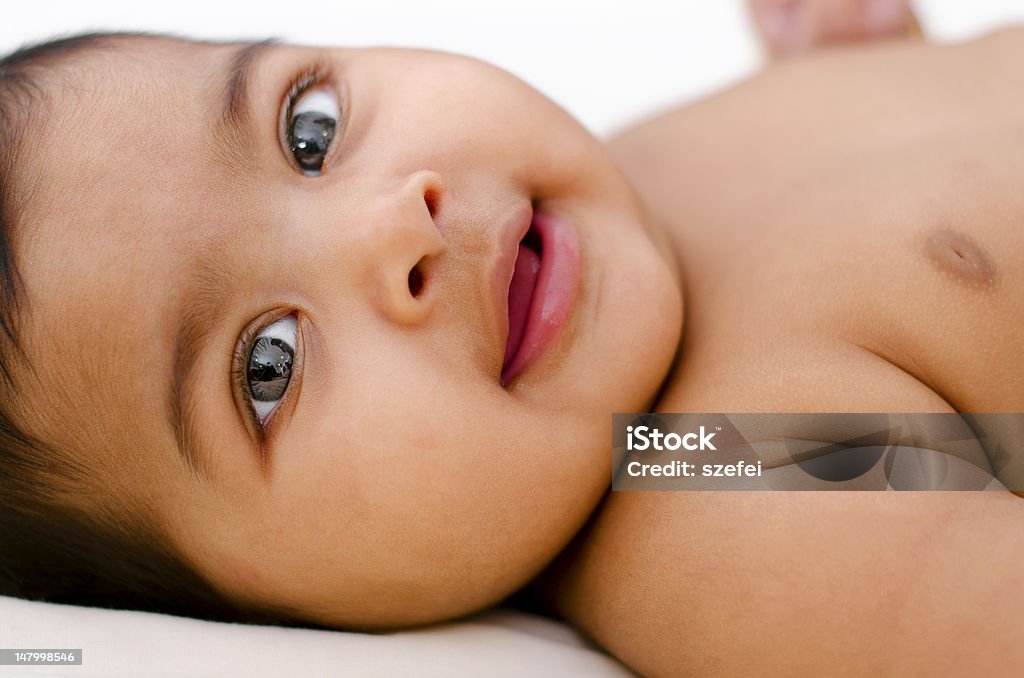 Indian baby girl 6 months old Indian baby girl smiling, lying on bed. Baby - Human Age Stock Photo