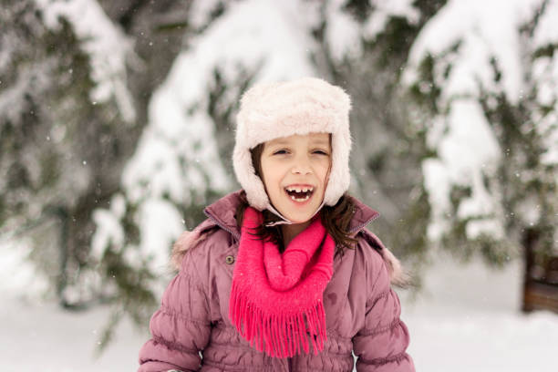 Cute little girl playing whit snow during winter day in the yard