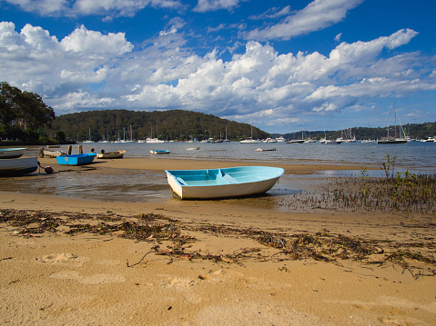 Church Point Reserve, Sydney, Australia - January 08 2022 : Small dinghy boats moored on the beach at low tide on a warm afternoon day.