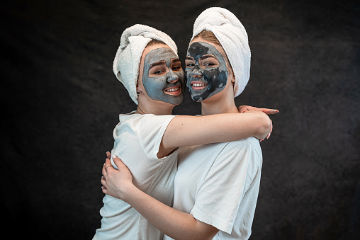 Friends female people make mud clay mask as anti aging treatment isolated on black. Spa wellness. Stay beautiful, healthcare grooming