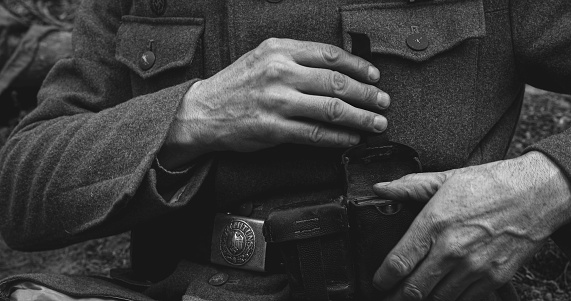 World War II German Soldier Cleaning Rifle. Soldier Preparing Weapon. German Military Ammunition Of A German WW2 Soldier. Black And White Colors