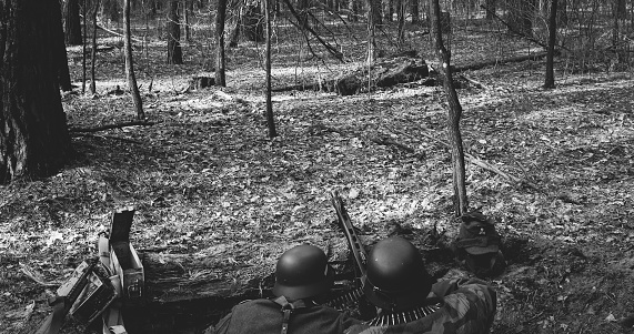 German Wehrmacht Infantry Soldier In World War II prepare for Shooting machine gun from Forest entrenchment. reload weapon. Black And White Colors