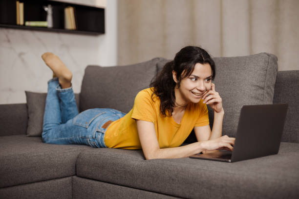 istock Happy indian or arabian young woman lying sofa and using laptop. Remote working 1479992331