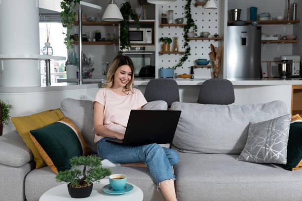istock Young freelancer woman wedding planner and counselor sitting on sofa drinking coffee and coming up with new ideas for clients as she reads and write what she has written from the wedding plans options 1479996608