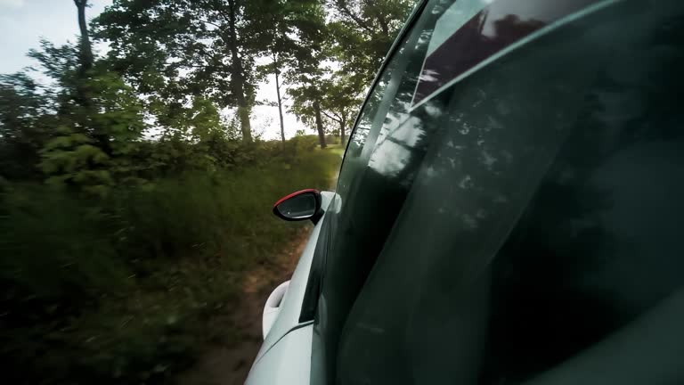 Close-up wheels spinning view from car side POV. Driving a car on the dirt country road at rapid speed