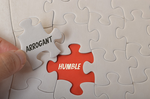 Jigsaw puzzle with text ARROGANT and HUMBLE.
