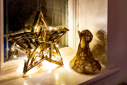 Gold star and angel Christmas decorations on a window sill.