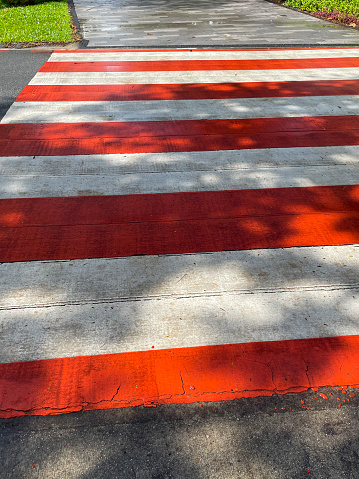 Stock photo showing close-up, elevated view of pedestrian road crossing with painted road markings on tarmac surface.