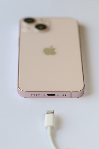 An iPhone 13 mini pink with Lightning cable