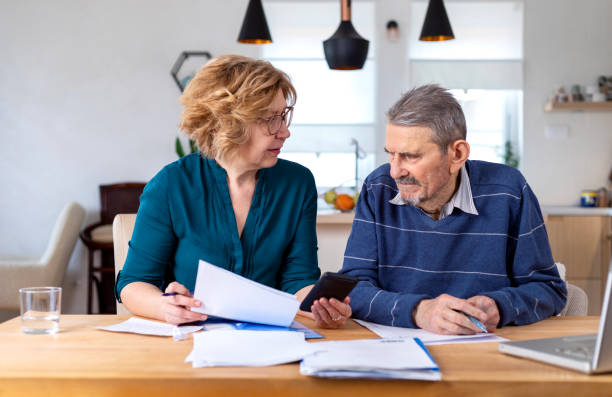 Woman Helping a Senior  Man With Documents And Bills stock photo