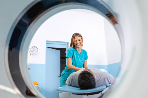 istock Doctor preparing patient for CT scanner. Senior man going into CT scanner. CT scan technologist overlooking patient in Computed Tomography scanner during preparation for procedure 1480008765