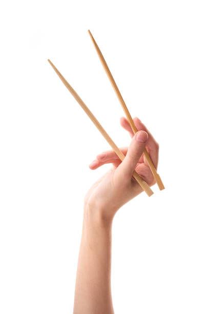 mano femenina palillos de madera aislados sobre fondo blanco. - chopsticks fotografías e imágenes de stock