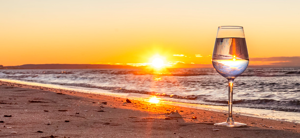 Reflection in a glass at sunset on a beach.