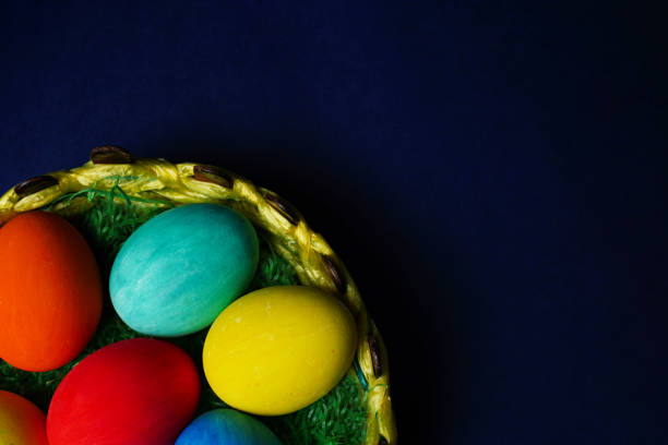Easter composition. Colorful easter eggs in basket on blue background. The minimal concept. Flat lay. Copy space.