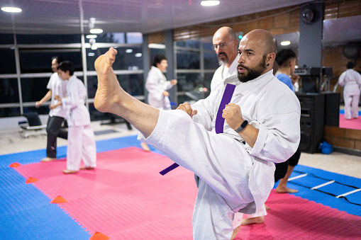 Mid adult man kicking during a karate class