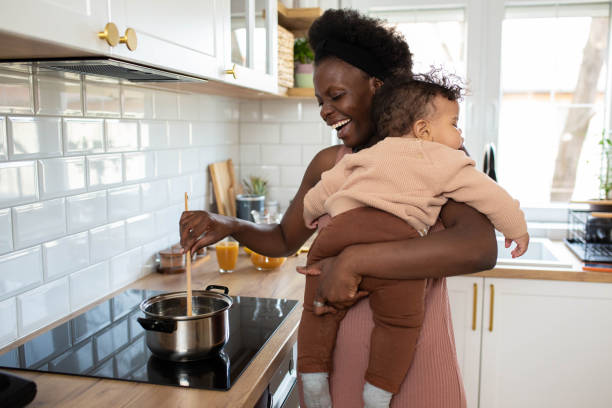 istock Multitasking mum holding her sleeping baby while she makes food in her kitchen 1480016072