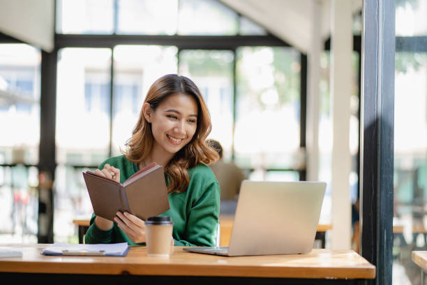 istock young woman working in a cafe using laptop and drinking coffee Asian female student using a computer for distance learning sitting on a bench in the shop casual lifestyle people and technology lifestyle 1480017702