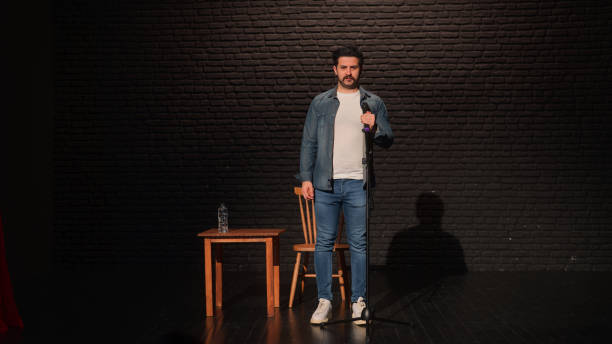 Portrait of a male stand-up comedian talking on stage A portrait of a male stand-up comedian is talking on stage. comedian stock pictures, royalty-free photos & images