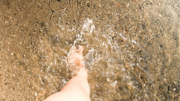 istock Male feet stepping in sea wave on sandy beach 1480020319