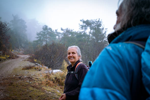 istock Elderly couple walking on forest soil forest path in fog. 1480020670
