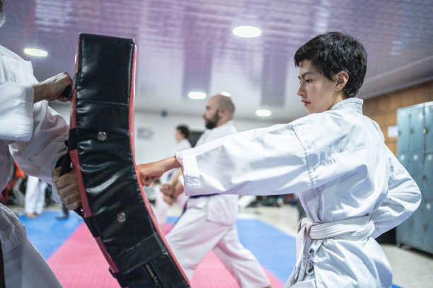 un enfant s’entraîne sur un sac de boxe au cours de karaté - karate punching bag caucasian leisure activity photos et images de collection