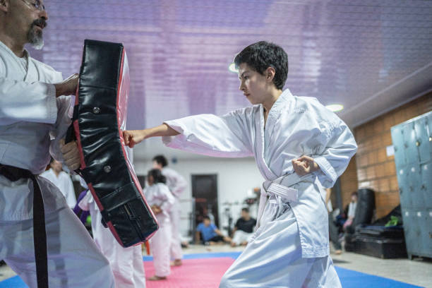 un enfant s’entraîne sur un sac de boxe au cours de karaté - karate punching bag caucasian leisure activity photos et images de collection