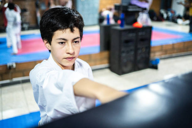 un enfant s’entraîne sur un sac de boxe au cours de karaté - karate punching bag caucasian leisure activity photos et images de collection