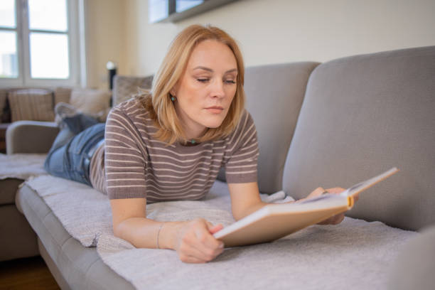 istock Woman reading book at home 1480024365