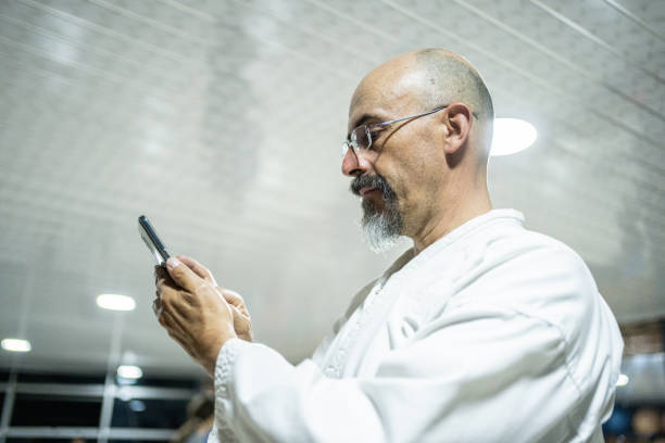 Mature man using mobile phone at karate gym