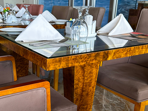 Stock photo showing the interior of a restaurant with highly polished tiled marble floor, window glass wall and glass topped tables.