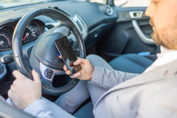 handsome businessman uses a mobile phone while driving - thirty pieces of silver imagens e fotografias de stock